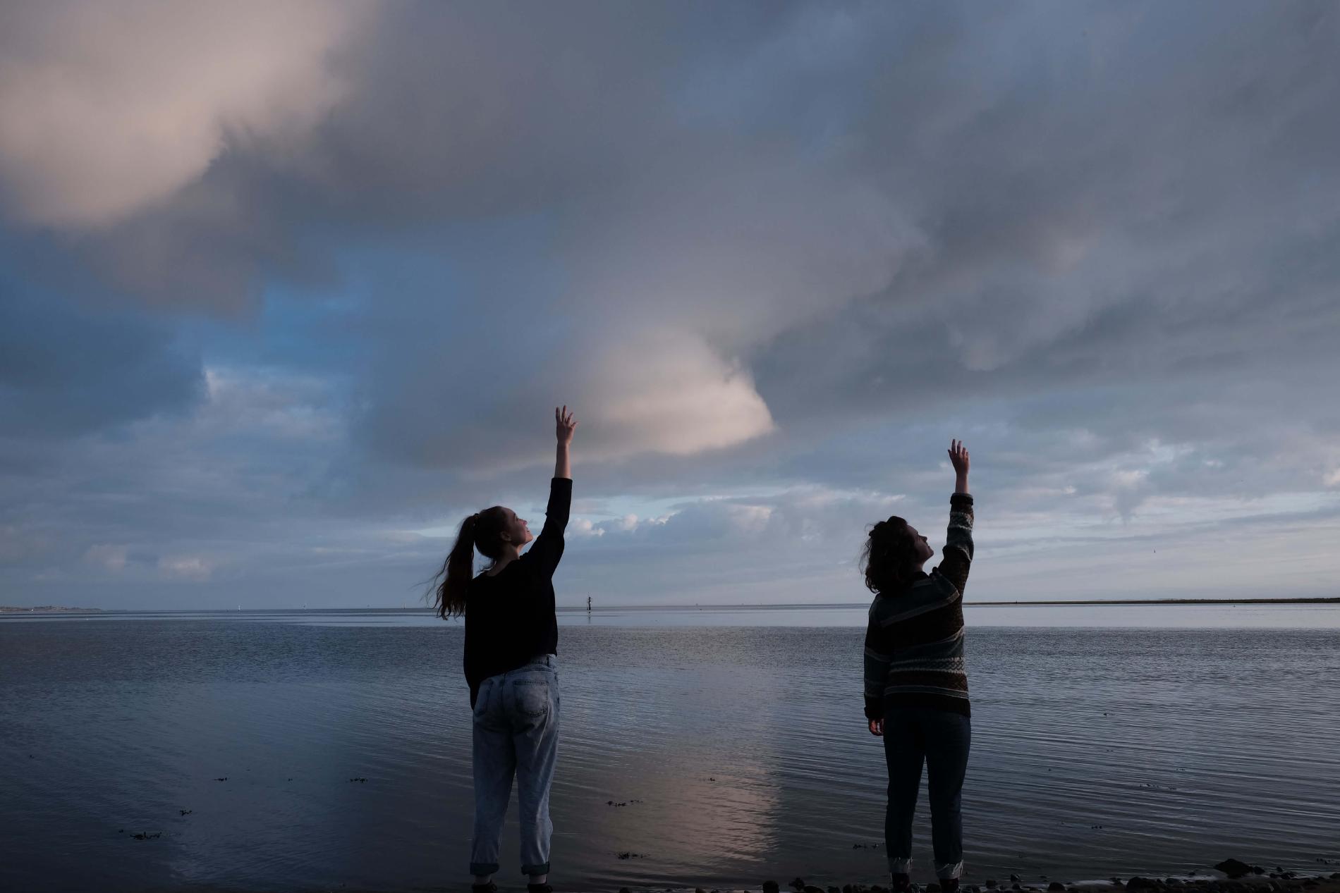 Rae Emily George reaching for the sky on a beach